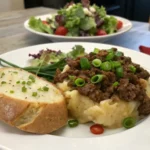 Plated ground beef and potato recipe with green onions and salad
